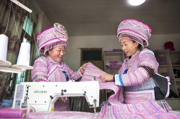 1月10日，贵州省黔西市红林彝族苗族乡鱼塘村一家苗族服饰加工车间，村民在制衣过程中进行交流。