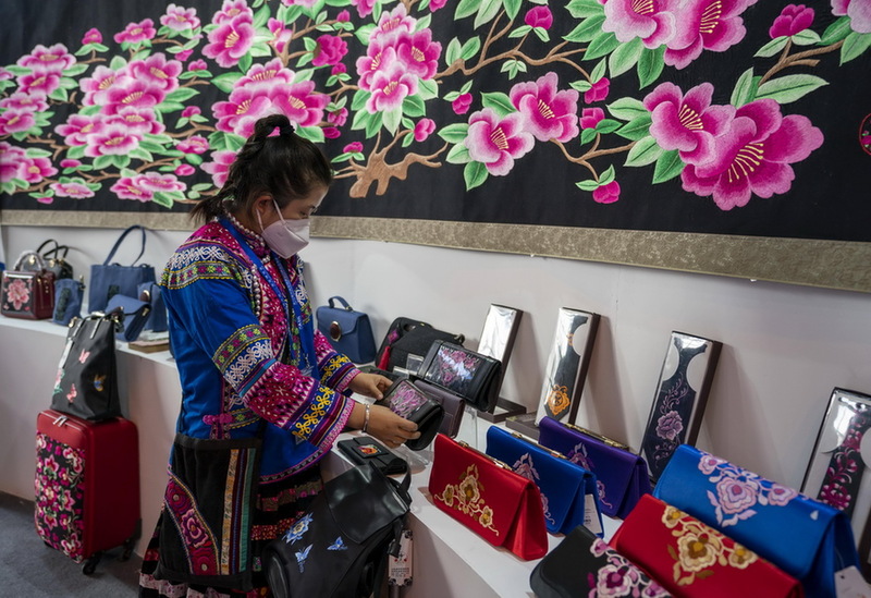 11月20日，一名参展商在南博会旅游文化馆内整理彝绣展品。
