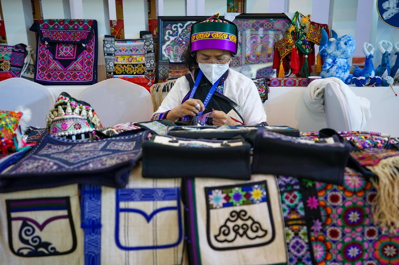 11月20日，一名彝绣传承人在南博会旅游文化馆内进行刺绣展示。